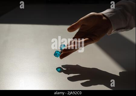 Frau wirft ein Paar blaue transparente Würfel. Stockfoto