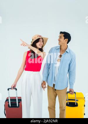Aufregende Reise, glücklicher Urlaub. Sommerurlaub. Asiatische Paar Reisende suchen einander mit spannenden, Mann und junge Frau zeigen mit Koffern Stockfoto