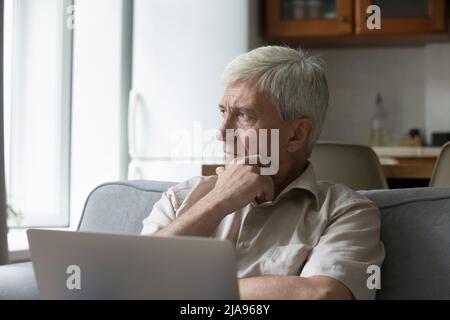 Nachdenklich gealterte Männer fühlen sich unsicher hat Zweifel an der Arbeit auf Laptop Stockfoto