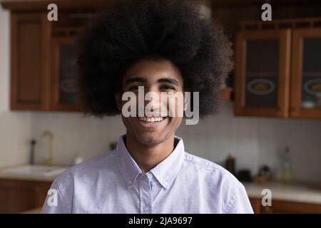 Der junge schwarze Mann blickt mit einem selbstbewussten breiten Lächeln auf die Kamera Stockfoto