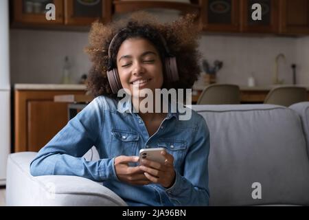 Happy Gen Z Teenager afrikanisches Mädchen in großen kabellosen Kopfhörern Stockfoto