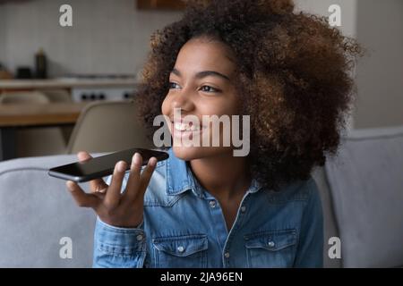 Glücklich verträumt afrikanisches Mädchen im Gespräch auf Handy auf Lautsprecher Stockfoto