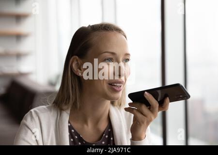 Glücklicher, nachdenklicher Smartphone-Benutzer, der Audionachrichten aufzeichnet Stockfoto