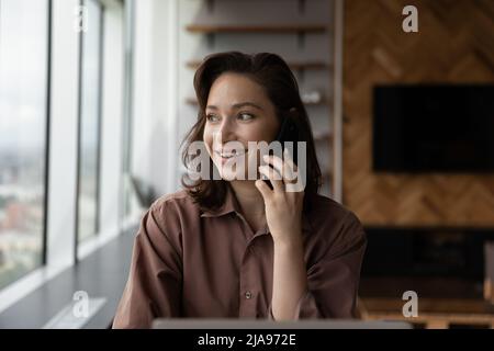 Glückliche Millennial Geschäftsfrau sprechen auf Handy mit nachdenklichen Gesicht Stockfoto