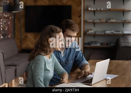 Zwei glückliche Geschäftsleute, die in einem modernen Büro einen Laptop verwenden Stockfoto