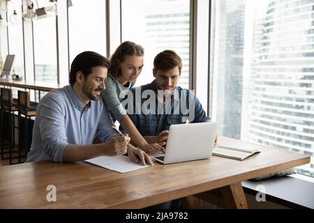 Kreatives Geschäftsteam, das im Büro einen Laptop teilt Stockfoto