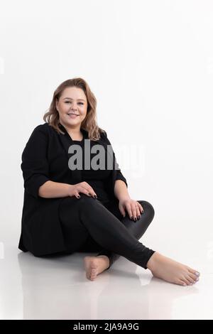 Vertikale lächelnde und freundliche blonde Frau mit perfekter Haut im Studio. Körper positiv, sich selbst lieben. Gesundheit, Körperpflege Stockfoto