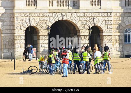 Eine Gruppe von Touristen, die auf einer Fahrradtour mit gut sichtbaren Jacken auf dem historischen Horse Guards Parade Ground für einen Fotostopp in London England, Großbritannien, unterwegs sind Stockfoto