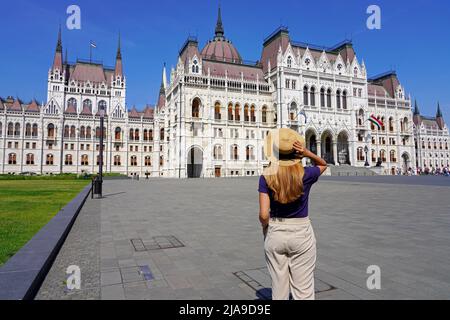 Majestätischer Palast des ungarischen Parlaments in Budapest, Ungarn. Junge Touristenfrau, die die Schönheiten Europas entdeckt. Stockfoto