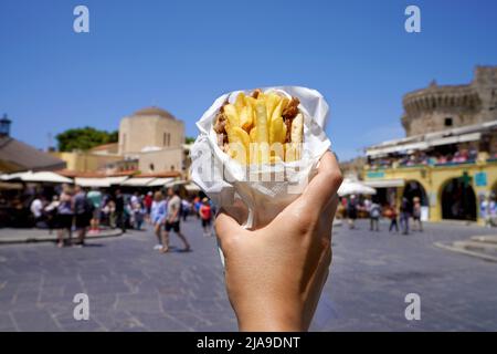 Pita Gyros. Griechische Gyros, eingewickelt in Pita-Brote, gegen den Platz der griechischen Altstadt. Stockfoto