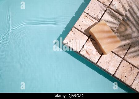 Swimmingpool, Blick von oben im Hintergrund. Wasserring und Palmschatten auf Travertin-Stein Stockfoto