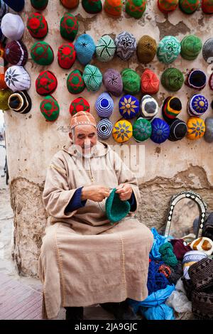 Alter Mann strickt und häkelt Hüte zum Verkauf. Traditionell Marokkanisch. Markt Souk Essaouira Stockfoto