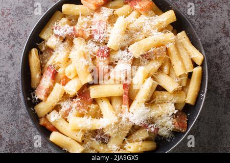 Pasta alla Gricia typisch italienische Pasta mit Pecorino-Käse und Guanciale in der Nähe auf dem Teller auf dem Tisch. Horizontale Draufsicht von oben Stockfoto