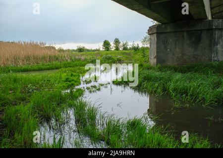 Landschaft eines flachen Flusses unter einer Brücke. Stockfoto