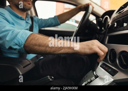 Nicht erkennbarer Mann, der in der Stadt ein neues Auto fährt Stockfoto