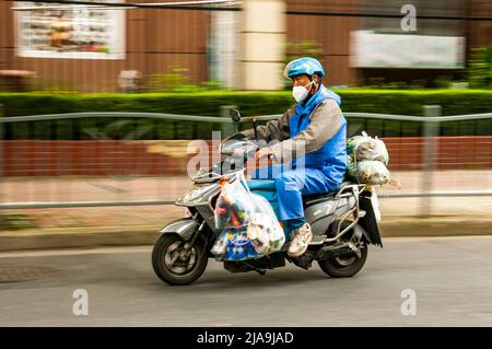 Ein Lieferfahrer, der Lebensmittel im Putuo District, Shanghai, China, während des Endes der Sperre Shanghais liefert. Stockfoto