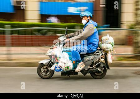 Ein Lieferfahrer, der Lebensmittel im Putuo District, Shanghai, China, während des Endes der Sperre Shanghais liefert. Stockfoto