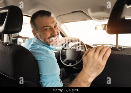 Lächelnder Mann, der in der Stadt ein neues Auto fährt Stockfoto