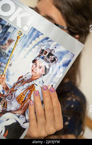 Fächer mit Fingernägeln, die mit der britischen Flagge bemalt sind und eine Kopie des Magazins OK mit einem Bild der Krönung der Königin halten. Platinum Jubilee Juni 2022 Stockfoto
