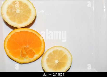 Zitronen- und Orangenscheiben auf weißem Teller. Stockfoto