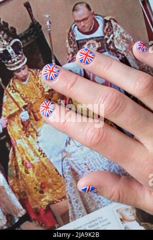 Frau mit Fingernägeln, gemalt mit der britischen Flagge, die auf dem OK-Magazin ruht, mit einem Bild aus der Krönung der Königin. Platinum Jubilee Juni 2022 Stockfoto