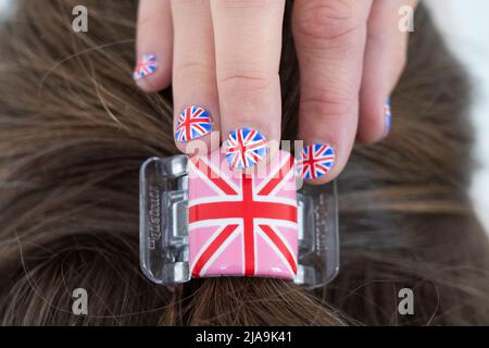 Fan von Queen Elizabeth mit verzierten Fingernägeln mit der britischen Flagge und einem Haarclip mit dem Union Jack, der für die Feier des Platin-Jubiläums bereit ist Stockfoto