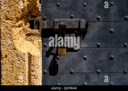 Rostiger eiserner Verschluss an der Holztür mit runden Metallknöpfen. Stockfoto