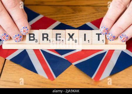 Die Fingernägel der Frau sind mit Union Jacks geschmückt, die auf britischen Flaggen abgekratzt Buchstaben halten, die den Brexit ausweisen. Konzept - Brexit-Feier Stockfoto