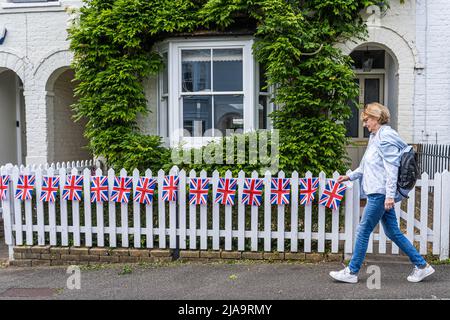 London, 29. Mai 2022. Ein Fußgänger geht an Union Jack-Ammer vorbei, die auf einem weißen Pfostenzaun vor einem Wohneigentum im Dorf Wimbledon gezeigt wird, um das Platin-Jubiläum von Königin Elizabeth II zu feiern. Kredit. amer Ghazzal/Alamy Live Nachrichten Stockfoto