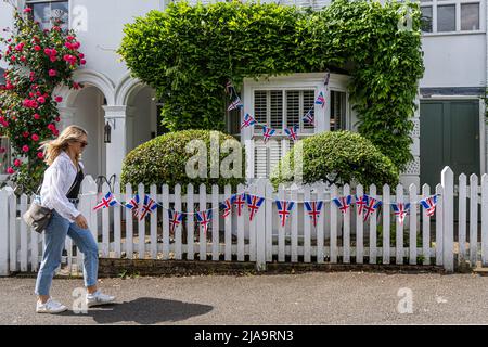 London, 29. Mai 2022. Ein Fußgänger geht an Union Jack-Ammer vorbei, die auf einem weißen Pfostenzaun vor einem Wohneigentum im Dorf Wimbledon gezeigt wird, um das Platin-Jubiläum von Königin Elizabeth II zu feiern. Kredit. amer Ghazzal/Alamy Live Nachrichten Stockfoto