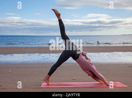 Portobello, Edinburgh Schottland, Großbritannien. 29. Mai 2022. Yoga-Übungen am Sandstrand. Temperatur ca. 9 Grad Celsius. Stockfoto