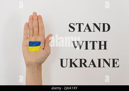 Nahaufnahme der Handfläche eines Weibchens mit der ukrainischen Nationalflagge. Stand mit Ukraine-Slogan auf weißem Hintergrund. Heben Sie die Hand Stockfoto