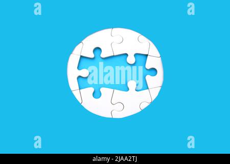 Rahmen aus weißen Puzzles auf blauem Hintergrund. Ort für Ihren Text. Modell Stockfoto