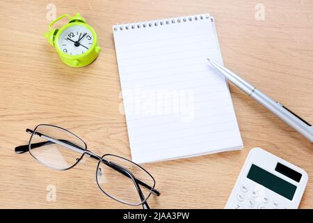 Leeres Notizbuch, Stift, Wecker auf Holzschreibtisch Stockfoto