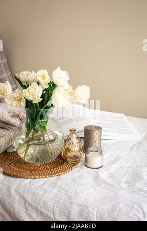 Home Komposition mit einem Bouquet aus Tulpen in einer Glasvase und Kerzen. Stockfoto