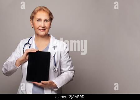Lächelnde Ärztin oder Krankenschwester, die einen Tablet-pc zeigt Stockfoto