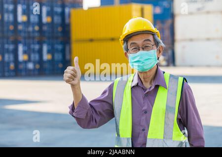 Gesunder älterer Arbeiter mit Gesichtsmaske, Daumen nach oben. Asiatischer chinesischer alter Mann Ingenieur Mitarbeiter Vorarbeiter gute Gesundheitsversorgung. Stockfoto