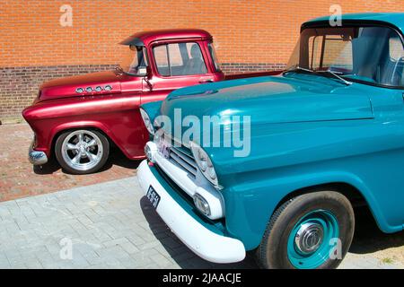 Vorderseite eines blauen und eines roten Vintage Chevrolet Pickups vom 1950s auf einer Oldtimer-Ausstellung in Uithuizen, Groningen, Niederlande. Stockfoto
