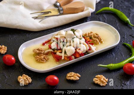 Speziell zubereiteter Frühstückskäse. Eine spezielle Käseplatte, zubereitet mit Olivenöl, Gemüse, Walnüssen und Käse. Nahaufnahme Stockfoto