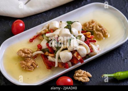 Speziell zubereiteter Frühstückskäse. Eine spezielle Käseplatte, zubereitet mit Olivenöl, Gemüse, Walnüssen und Käse. Nahaufnahme Stockfoto