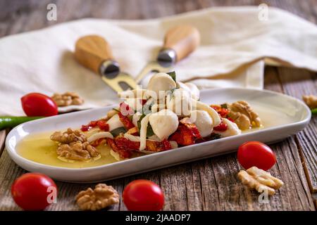 Speziell zubereiteter Frühstückskäse. Eine spezielle Käseplatte, zubereitet mit Olivenöl, Gemüse, Walnüssen und Käse. Nahaufnahme Stockfoto