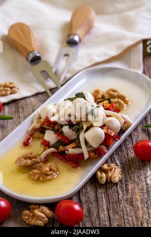 Speziell zubereiteter Frühstückskäse. Eine spezielle Käseplatte, zubereitet mit Olivenöl, Gemüse, Walnüssen und Käse. Nahaufnahme Stockfoto