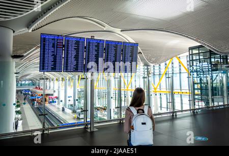 Passagierin mit Rucksack, Blick auf den Fahrplan für internationale Abflüge Tableau am Flughafen Istanbul Havalimani - IST Airport interior, Türkei Stockfoto