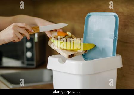 Frau wirft Gemüseschnitzel in einen Komposteimer. Nahaufnahme. Stockfoto