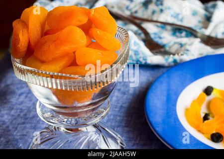 Draufsicht auf eine Schüssel mit süßen, getrockneten türkischen Aprikosen, hinterleuchtet und auf einem dunkelblauen Hintergrund platziert. Stockfoto