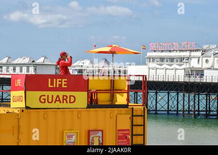 Brighton UK 29. May 2022 - Ein Rettungsschwimmer beobachtet, wie Besucher die Sonne an der Küste und am Strand von Brighton genießen, während für Großbritannien in den nächsten Tagen kühleres Wetter prognostiziert wird : Credit Simon Dack / Alamy Live News Stockfoto