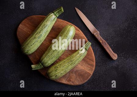 Frische Zucchini auf Holzschneidebrett mit Messer Stockfoto