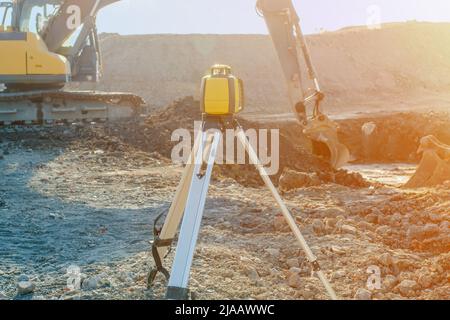 Rotierende Laser-Vermessungsgeräte auf der Baustelle mit Baggergruben Fundament im Hintergrund gesetzt. Laserpegel als Schlüsselgerät zum Pegel Stockfoto