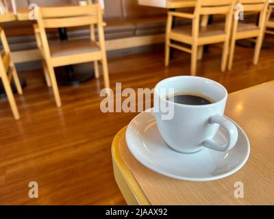 Schwarzer Kaffee in einer weißen Tasse und Untertasse auf einem Holztisch Stockfoto