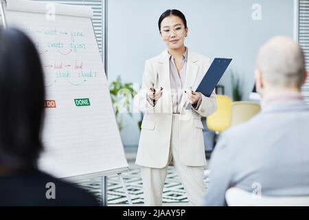 Porträt einer jungen asiatischen Frau, die im Büro Englischunterricht erteilt und am Whiteboard mit dem Publikum spricht Stockfoto